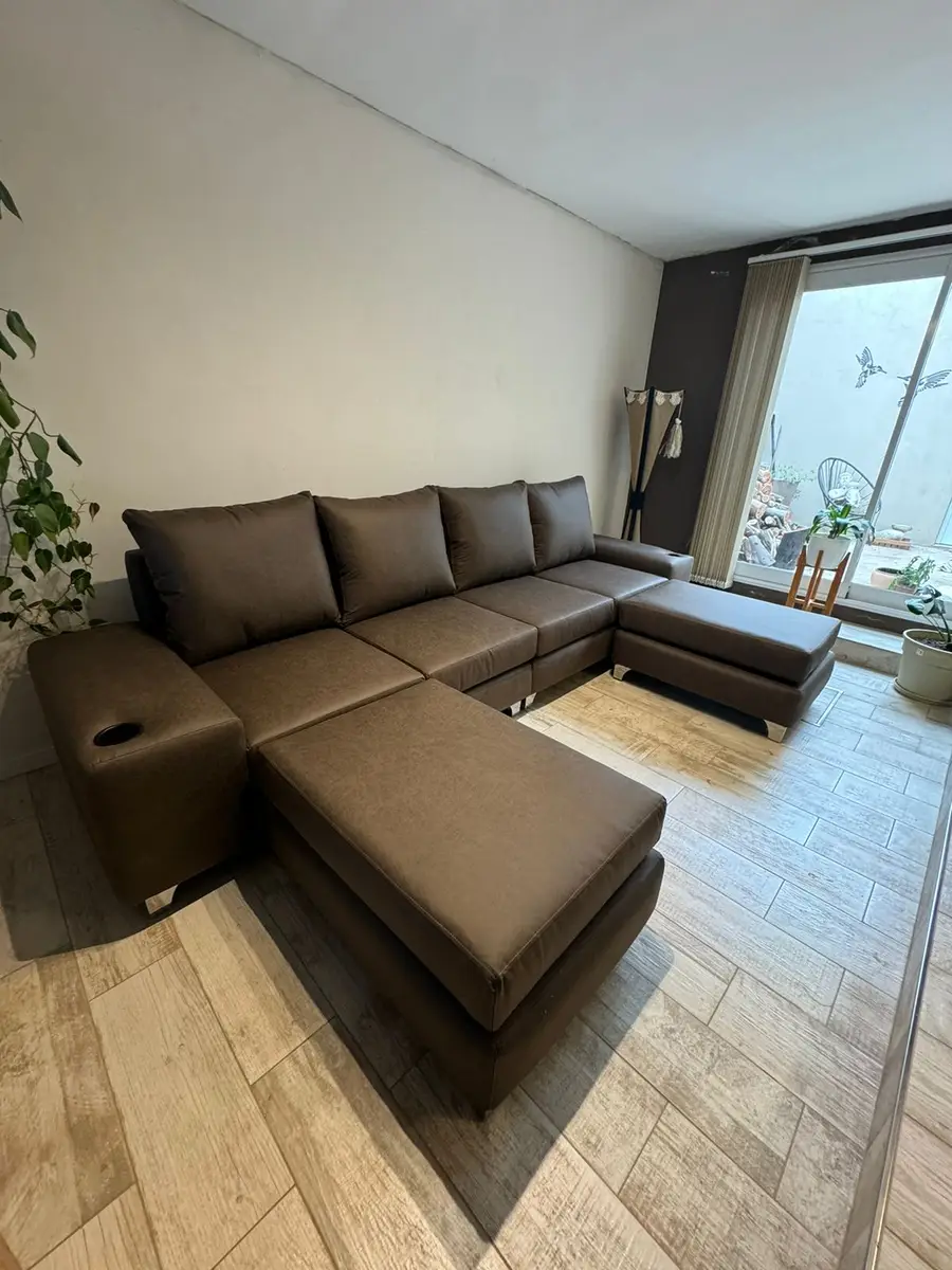 Sillón en U de cuero marrón con dos camastros en un living